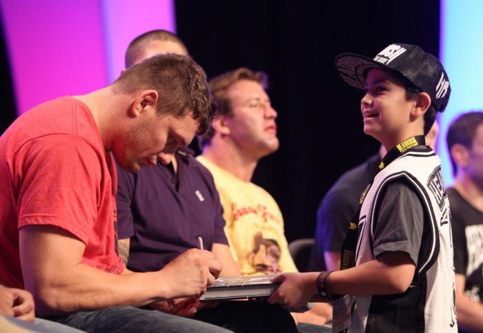 Matt Mitrione signs an autograph for a young fan during a Q&A session at the UFC Fan Expo
