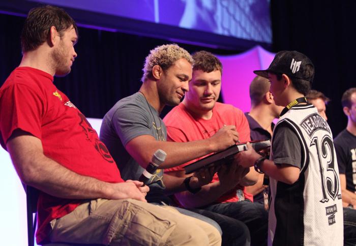 Josh Koscheck signs an autograph for a young fan during a Q&A session at the UFC Fan Expo