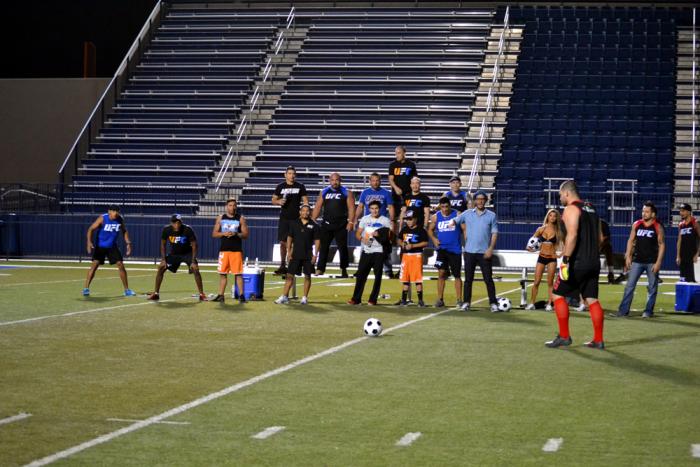 Cain Velásquez se apresta a pegarle al balón mientras ambos equipos lo observan