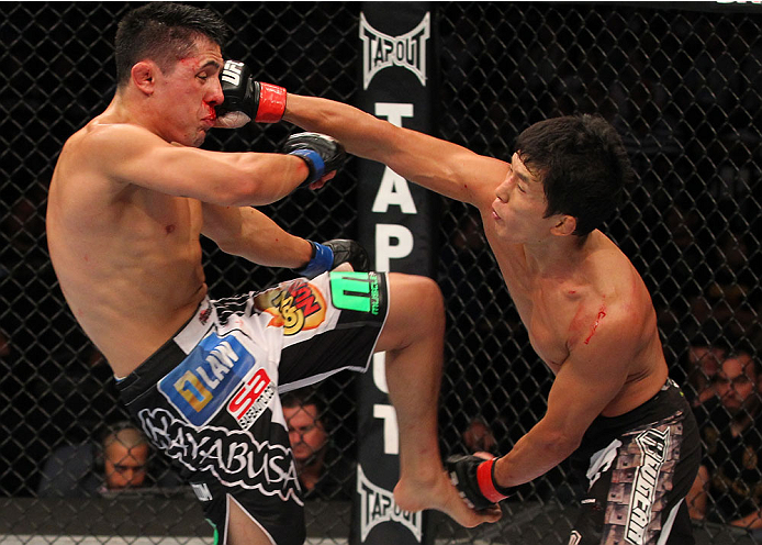 INDIANAPOLIS, IN - AUGUST 28: (R-L) Takeya Mizugaki punches Erik Perez in their bantamweight fight during the UFC on FOX Sports 1 event at Bankers Life Fieldhouse on August 28, 2013 in Indianapolis, Indiana. (Photo by Ed Mulholland/Zuffa LLC/Zuffa LLC vi