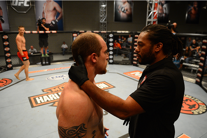 LAS VEGAS, NV - OCTOBER 16: (R-L) Referee Herb Dean checks on Daniel Vizcaya after he was knocked down by Matt Van Buren in their elimination fight during filming of season nineteen of The Ultimate Fighter on October 16, 2013 in Las Vegas, Nevada. (Photo