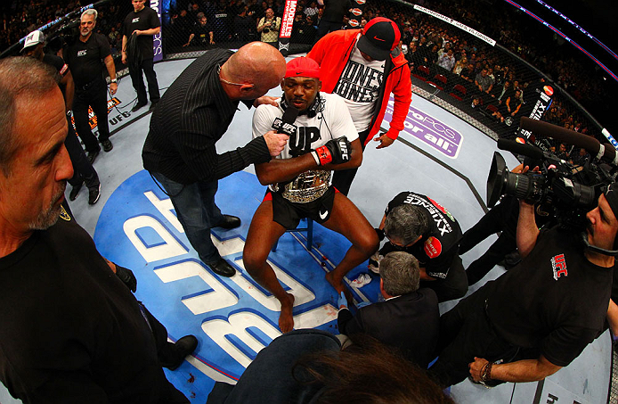 NEWARK, NJ - APRIL 27: Jon Jones (C) has his broken toe tended to while he is interviewed by Joe Rogan (R) after winning by knockout in round one against Chael Sonnen in their light heavyweight championship bout during the UFC 159 event at the Prudential