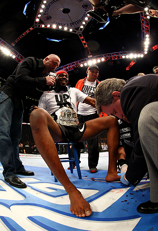 NEWARK, NJ - APRIL 27: Jon Jones (C) has his broken toe tended to while he is interviewed by Joe Rogan (R) after winning by knockout in round one against Chael Sonnen in their light heavyweight championship bout during the UFC 159 event at the Prudential
