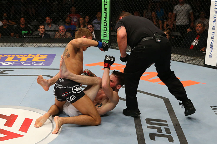 SAN ANTONIO, TX - JUNE 28: Cody Gibson (black shorts) punches Johnny Bedford as the referee looks on in their bantamweight bout at the AT&T Center on June 28, 2014 in San Antonio, Texas. (Photo by Ed Mulholland/Zuffa LLC/Zuffa LLC via Getty Images)