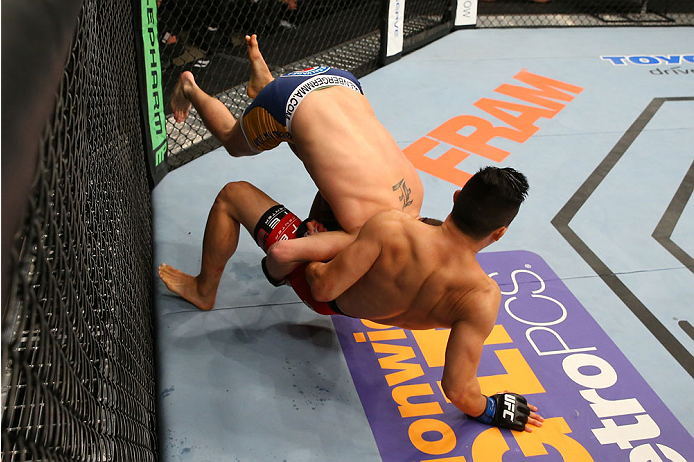 SAN ANTONIO, TX - JUNE 28: Joe Ellenberger (blue shorts) takes down James Moontasri in their lightweight bout at the AT&T Center on June 28, 2014 in San Antonio, Texas. (Photo by Ed Mulholland/Zuffa LLC/Zuffa LLC via Getty Images)