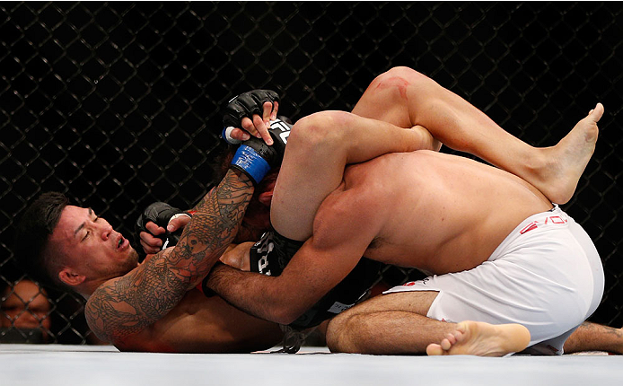 SINGAPORE - JANUARY 04: (L-R) Russell Doane secures a triangle choke submission against Leandro Issa in their bantamweight bout during the UFC Fight Night event at the Marina Bay Sands Resort on January 4, 2014 in Singapore. (Photo by Josh Hedges/Zuffa L