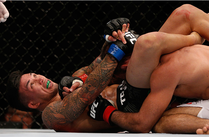 SINGAPORE - JANUARY 04: (L-R) Russell Doane secures a triangle choke submission against Leandro Issa in their bantamweight bout during the UFC Fight Night event at the Marina Bay Sands Resort on January 4, 2014 in Singapore. (Photo by Josh Hedges/Zuffa L