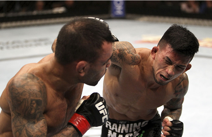 SINGAPORE - JANUARY 04: (L and R) Leandro Issa tries to avoid a show from Russell Doane in their bantamweight bout during the UFC Fight Night event at the Marina Bay Sands Resort on January 4, 2014 in Singapore. (Photo by Mitch Viquez/Zuffa LLC/Zuffa LLC