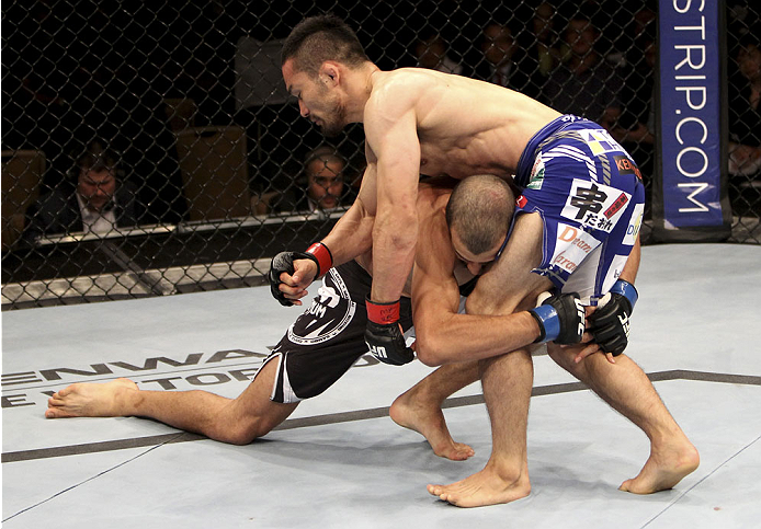 SINGAPORE - JANUARY 04: Quinn Mulhern goes for a takedown on Katsunori Kikuno in their lightweight bout during the UFC Fight Night event at the Marina Bay Sands Resort on January 4, 2014 in Singapore. (Photo by Mitch Viquez/Zuffa LLC/Zuffa LLC via Getty