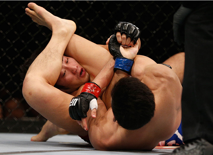 SINGAPORE - JANUARY 04: (R-L) Kang Kyung Ho attempts an arm bar submission against Shunichi Shimizu in their bantamweight bout during the UFC Fight Night event at the Marina Bay Sands Resort on January 4, 2014 in Singapore. (Photo by Josh Hedges/Zuffa LL