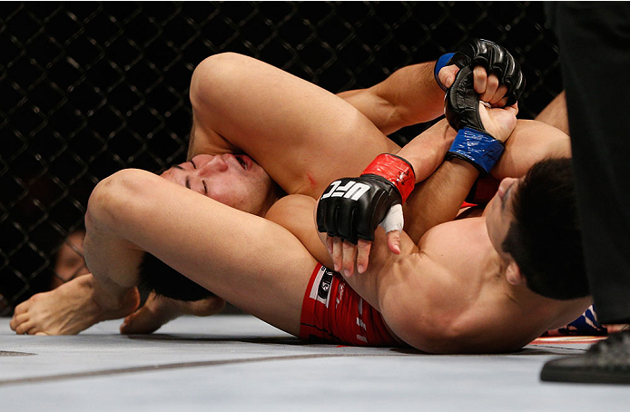 SINGAPORE - JANUARY 04: (R-L) Kang Kyung Ho attempts an arm bar submission against Shunichi Shimizu in their bantamweight bout during the UFC Fight Night event at the Marina Bay Sands Resort on January 4, 2014 in Singapore. (Photo by Josh Hedges/Zuffa LL