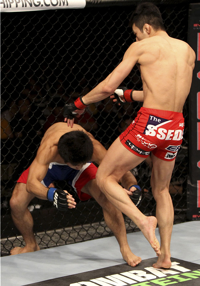 SINGAPORE - JANUARY 04: Kang Kyung Ho goes for a knee on Shunichi Shimizu in their bantamweight bout during the UFC Fight Night event at the Marina Bay Sands Resort on January 4, 2014 in Singapore. (Photo by Mitch Viquez/Zuffa LLC/Zuffa LLC via Getty Ima