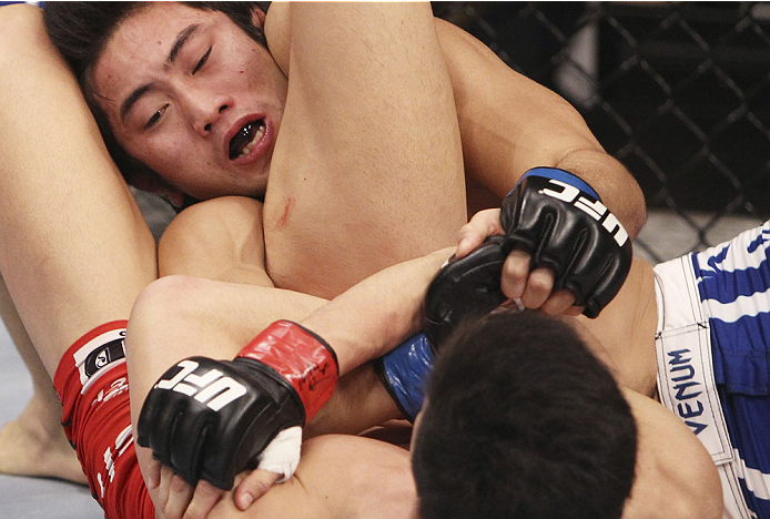 SINGAPORE - JANUARY 04: Kang Kyung Ho(closest) goes for a submission attempt on Shunichi Shimizu in their bantamweight bout during the UFC Fight Night event at the Marina Bay Sands Resort on January 4, 2014 in Singapore. (Photo by Mitch Viquez/Zuffa LLC/