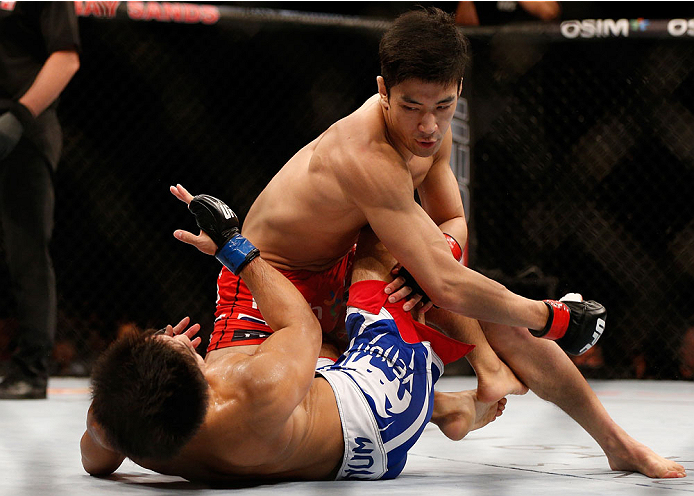 SINGAPORE - JANUARY 04: (R-L) Kang Kyung Ho punches Shunichi Shimizu in their bantamweight bout during the UFC Fight Night event at the Marina Bay Sands Resort on January 4, 2014 in Singapore. (Photo by Josh Hedges/Zuffa LLC/Zuffa LLC via Getty Images)