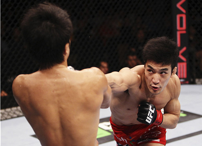 SINGAPORE - JANUARY 04: Kang Kyung Ho goes for a punch on Shunichi Shimizu in their bantamweight bout during the UFC Fight Night event at the Marina Bay Sands Resort on January 4, 2014 in Singapore. (Photo by Mitch Viquez/Zuffa LLC/Zuffa LLC via Getty Ima
