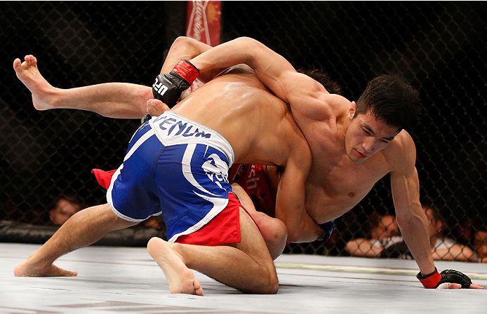 SINGAPORE - JANUARY 04: (L-R) Shunichi Shimizu takes down Kang Kyung Ho in their bantamweight bout during the UFC Fight Night event at the Marina Bay Sands Resort on January 4, 2014 in Singapore. (Photo by Josh Hedges/Zuffa LLC/Zuffa LLC via Getty Images