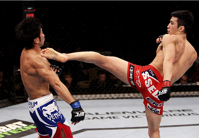 SINGAPORE - JANUARY 04: Kang Kyung Ho goes for a kick on Shunichi Shimizu in their bantamweight bout during the UFC Fight Night event at the Marina Bay Sands Resort on January 4, 2014 in Singapore. (Photo by Mitch Viquez/Zuffa LLC/Zuffa LLC via Getty Imag