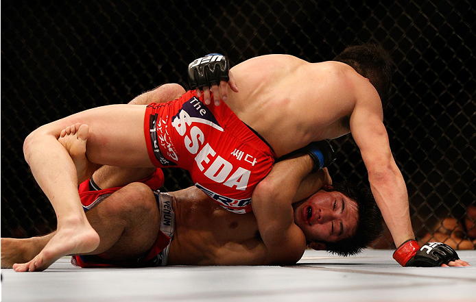 SINGAPORE - JANUARY 04: (R-L) Shunichi Shimizu attempts to reverse Kang Kyung Ho in their bantamweight bout during the UFC Fight Night event at the Marina Bay Sands Resort on January 4, 2014 in Singapore. (Photo by Josh Hedges/Zuffa LLC/Zuffa LLC via Get