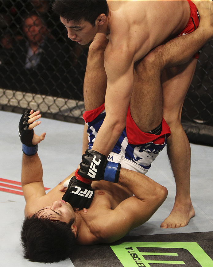 SINGAPORE - JANUARY 04: Kang Kyung Ho lands a punch on Shunichi Shimizu in their bantamweight bout during the UFC Fight Night event at the Marina Bay Sands Resort on January 4, 2014 in Singapore. (Photo by Mitch Viquez/Zuffa LLC/Zuffa LLC via Getty Images