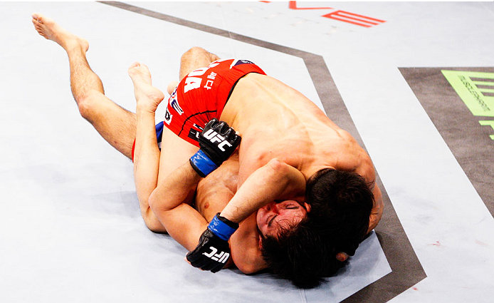 SINGAPORE - JANUARY 04: Kang Kyung Ho finishes off Shunichi Shimizu with an arm triangle submission in their bantamweight bout during the UFC Fight Night event at the Marina Bay Sands Resort on January 4, 2014 in Singapore. (Photo by Mitch Viquez/Zuffa L