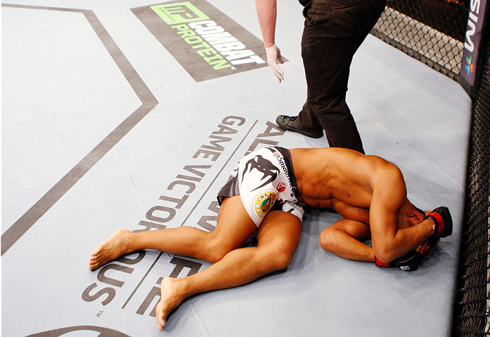 SINGAPORE - JANUARY 04: Kiichi Kunimoto lies on the ground after illegal elbows to the back of the head from his opponent, Luiz Dutra, in their welterweight bout during the UFC Fight Night event at the Marina Bay Sands Resort on January 4, 2014 in Singap