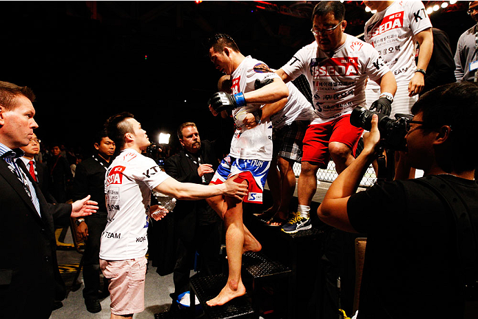 SINGAPORE - JANUARY 04: Lim Hyun Gyu is helped down the steps after his five round fight with Tarec Saffiedine in their welterweight bout during the UFC Fight Night event at the Marina Bay Sands Resort on January 4, 2014 in Singapore. (Photo by Mitch Vi