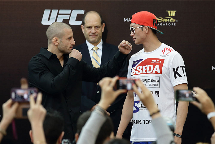 SINGAPORE - JANUARY 02: Tarec Saffiedine (L) faces off with Lim Hyun Gyu (R) as Mark Fischer (C), managing director of UFC Asia, looks on during the UFC Fight Night Singapore Ultimate Media Day at the Skating Rink at The Shoppes at Marina Bay Sand on Jan